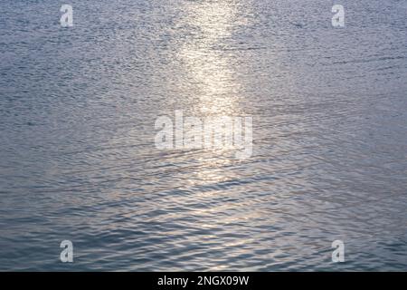 Detail eines Sonnenlichts, das im glitzernden Meer reflektiert wird. Funkelt im Wasser - Hintergrund. Meerwasser mit Sonnenblendung und Welligkeit. Kraftvolle und friedliche Natur c Stockfoto