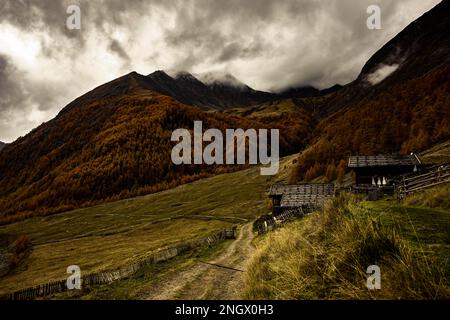 Alpenhütte in herbstlicher Berglandschaft mit bedrohlichem bewölktem Himmel, Pfossental, Merano, Vinschgau, Südtirol, Italien Stockfoto