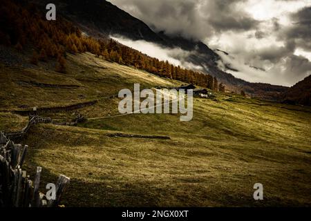 Alpenhütte in herbstlicher Berglandschaft mit bedrohlichem bewölktem Himmel, Pfossental, Merano, Vinschgau, Südtirol, Italien Stockfoto