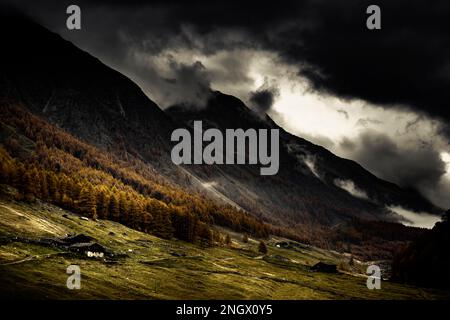 Alpenhütte in herbstlicher Berglandschaft mit bedrohlichem bewölktem Himmel, Pfossental, Merano, Vinschgau, Südtirol, Italien Stockfoto