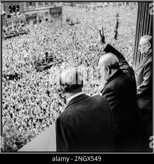 Der Premierminister Winston Churchill weht vor den ekstatischen Menschenmassen in Whitehall London den V-Sieg, während sie den VE Day am 8. Mai 1945 feiern. „Sieg in Europa“ vom Londoner Balkon des Gesundheitsministeriums überreicht Premierminister Winston Churchill mit seiner Markenzigarre sein berühmtes „V for Victory“-Zeichen an die massenhaften Menschenmassen in Whitehall am selben Tag, an dem er der britischen Nation den Sieg gegen Nazi-Deutschland übermittelte, am 8. Mai 1945 (VE Day). Zu Churchills Linker gehört Sir John Anderson, der Finanzminister. Zu Churchills Rechten ist Ernest Bevin, der Arbeitsminister. 8. Mai 1945 Stockfoto