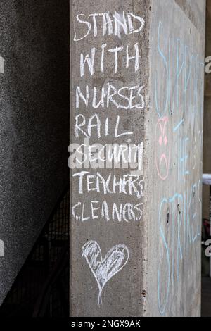 Stehen Sie zu den Krankenschwestern Eisenbahnsicherheit Lehrer Reinigungskräfte. Nachricht mit Kreide an der UCL-Gebäudewand während der UCU-Arbeitskampagne in London, England. Stockfoto