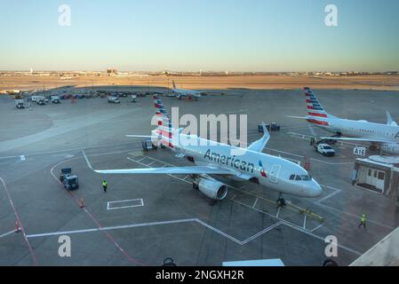 Zwei flugzeuge der amerikanischen Fluggesellschaften parkten am DFW International Airport mit der Start- und Landebahn hinter dem Sonnenuntergang Stockfoto