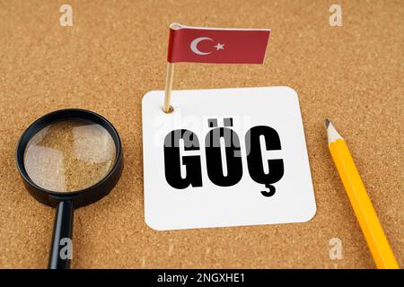 Auf dem Tisch liegt die Flagge der Türkei, ein Bleistift, eine Lupe und ein Blatt Papier mit einer ins Englische übersetzten Inschrift in Türkisch - Emigrat Stockfoto