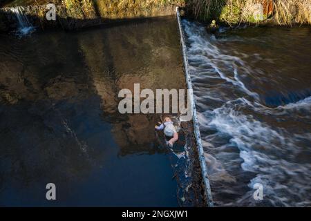 Die Kinderpuppe hat sich in einem Metalleinzugsgebiet in einem schnell fließenden Fluss verfangen. Stockfoto