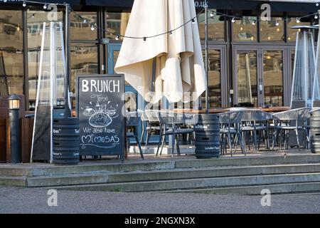 Der Speisesaal im Freien einer Bar, die an einem klaren, sonnigen Tag mit leeren Stühlen und Tischen für Brunch wirbt. Nach London Stockfoto