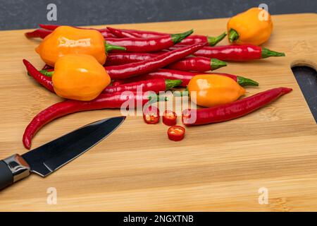 Sie schneiden heiße Paprika auf dem Schneidebrett der Küche. Konzept für die Erzeugung von heißem Pfeffer, frischem und biologischem Gemüse. Stockfoto