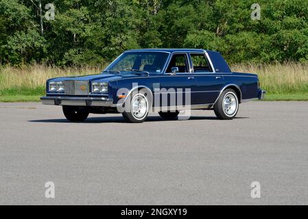 Ein dunkelblauer 1982 Chrysler New Yorker Fifth Avenue Edition Blick auf Bäume in heller Sonne. Stockfoto