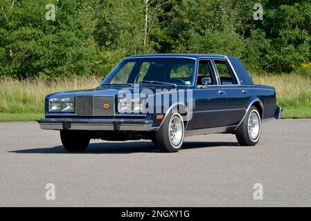 Ein dunkelblauer 1982 Chrysler New Yorker Fifth Avenue Edition Blick auf Bäume in heller Sonne. Stockfoto