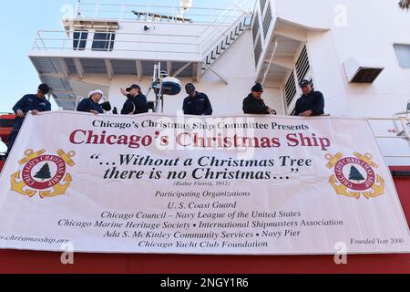 Besatzungsmitglieder an Bord der USCGC Mackinaw (WLBB 30) arbeiten mit einem Mitglied des Chicagoer Weihnachtsschiffkomitees zusammen, um ein Banner für die jährliche Entladung des Weihnachtsbaumschiffes 23. in Chicago am 1. Dezember 2022 aufzuhängen. Seit 22 Jahren in den USA Die Küstenwache hat mit mehreren Sponsoren zusammengearbeitet, um Familien aus Chicago Weihnachten zu liefern, die sonst vielleicht nicht in der Lage wären, eins zu bekommen. Stockfoto