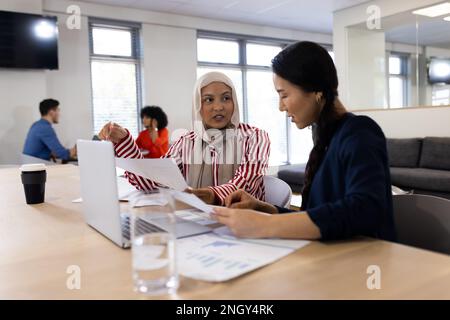 Bild von verschiedenen weiblichen Kollegen, die im Büro an einem Laptop arbeiten Stockfoto