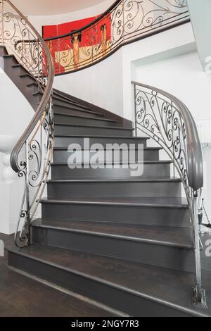 Nach einer spiralförmigen Holztreppe mit schmiedeeisernen Balustern auf den oberen Flur im luxuriösen Haus zu schauen. Stockfoto