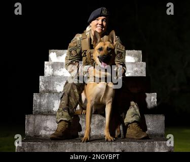 USA Air Force Staff Sgt. Shanna McCarter, 18. Security Forces Squadron, militärischer Hundeführer, posiert für ein Foto mit MWD Dina am Kadena Air Base, Japan, 1. Dezember 2022. McCarter war mehrere Jahre lang Polizistin, bevor sie zur Air Force kam. Sie sagte, sie wolle weiterhin Polizistin sein, weil sie gerne der Gemeinde hilft und sie beschützt. Stockfoto