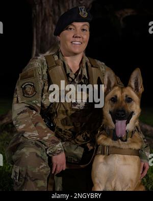 USA Air Force Staff Sgt. Shanna McCarter, 18. Security Forces Squadron, militärischer Hundeführer, posiert für ein Foto mit MWD Dina am Kadena Air Base, Japan, 1. Dezember 2022. MWD-Betreuer betreuen und trainieren ihren Hundepartner täglich und sind auch für ihr körperliches und emotionales Wohlbefinden verantwortlich. Stockfoto