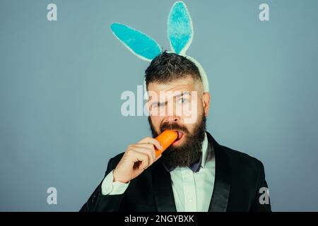 Frohen ostertag. Der Hasenmann frisst Karotten. Süßes Häschen Tragen Sie einen formellen Anzug oder Smoking. Wir feiern ostern. Party-Feier im Büro. Gesunder Snack Stockfoto