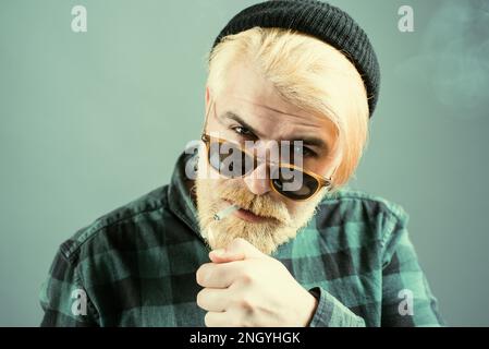 Mann raucht. Nahaufnahme eines jungen Mannes ohne Emotionen. Portrait hübscher Geschäftsmann mit selbstbewusster Gesichts. Stockfoto