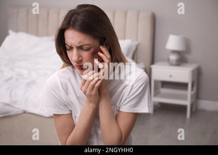 Frau mit Gesichtsverletzungen im Schlafzimmer. Opfer häuslicher Gewalt Stockfoto