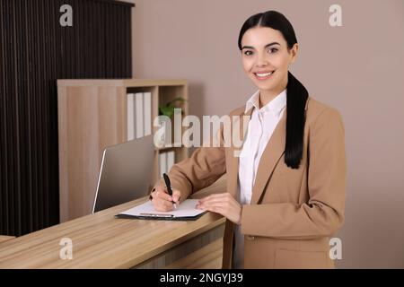 Rezeptionist mit Klemmbrett in der Nähe der Arbeitsfläche im Büro Stockfoto