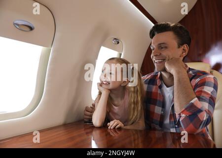 Vater mit Tochter, der während des Fluges aus dem Fenster im Flugzeug schaut Stockfoto