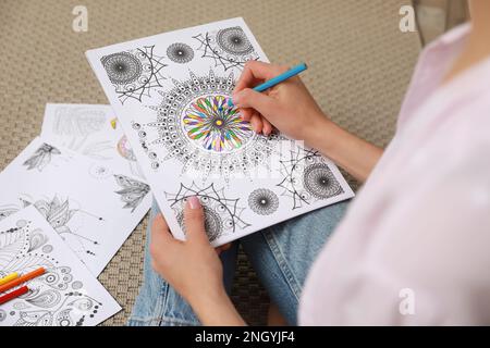 Junge Frau, die Anti-Stress-Seite auf dem Boden ausmalen, Nahaufnahme Stockfoto