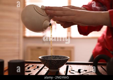 Meistern Sie es, während der traditionellen Teezeremonie am Tisch, in der Schließzeit, frisch gebrühtes Getränk in eine Tasse zu gießen Stockfoto