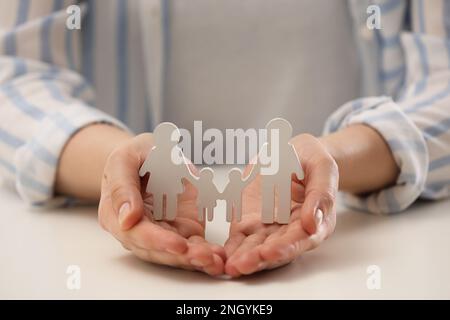 Eine Frau, die eine Familienfigur am weißen Tisch hält, Nahaufnahme Stockfoto