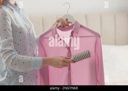 Eine junge Frau putzt zu Hause Kleider mit Fusselrolle, Nahaufnahme Stockfoto