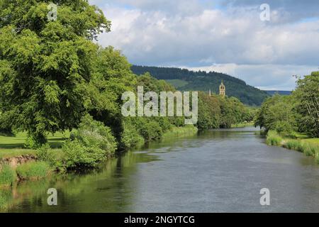 Blick auf den Fluss Tweed in Richtung der Innenstadt von Peebles von der Fotheringham Bridge im Sommer, Glentress Forest am Horizont. Sonniger Nachmittag mit Wolken Stockfoto