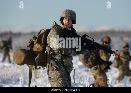 Soldaten der Universität Alaska, ROTC-Kadetten greifen ihr Ziel während einer Feldausbildung an der Joint Base Elmendorf-Richardson, Alaska, 2. Dezember 2022 an. Nach einer taktischen Lufteinführung manövrierten die Seawolf-Abschieberkadetten über schneebedecktes Gelände, griffen Oppositionstruppen an, sicherten sich ihr Ziel und beendeten mit einer Luftentführung. Alaska Army National Guard Piloten des 1-207. Aviation Regiment leisteten Luftunterstützung für das Training. Das General Support Aviation Battalion der AKARNG trainiert routinemäßig mit allen Zweigen des Militärs sowie mit zivilen Organisationen, um i zu verbessern Stockfoto