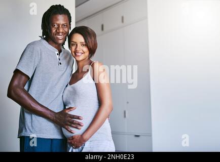 Wir gründen eine Familie. Ein junger Mann, der den Bauch seiner schwangeren Frau berührt. Stockfoto
