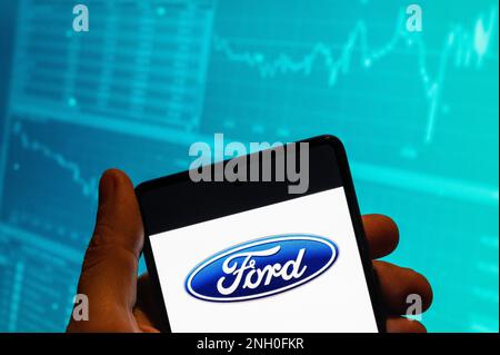 China. 15. Februar 2023. In dieser Fotoabbildung wird das Ford-Logo des amerikanischen multinationalen Automobilherstellers auf einem Smartphone mit einer Grafik des Börsenindex im Hintergrund angezeigt. (Foto: Budrul Chukrut/SOPA Images/Sipa USA) Guthaben: SIPA USA/Alamy Live News Stockfoto