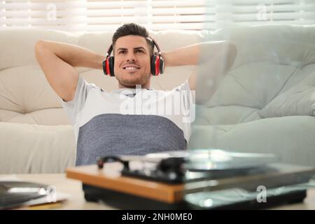 Glücklicher Mann, der zu Hause Musik mit Plattenspieler hört Stockfoto