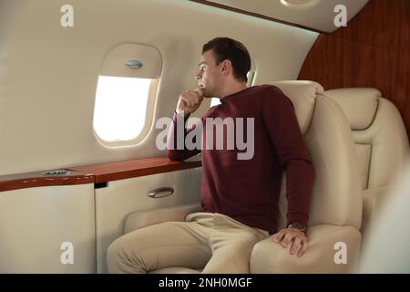 Nervöser junger Mann im Flugzeug. Aviophobie-Konzept Stockfoto