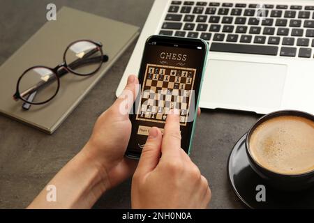 Frau, die online Schach auf einem Smartphone spielt, am Tisch, Nahaufnahme Stockfoto