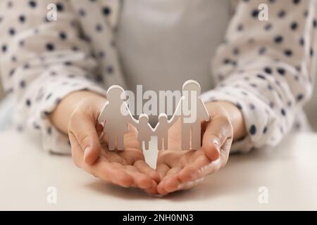 Eine Frau, die eine Familienfigur am weißen Tisch hält, Nahaufnahme Stockfoto