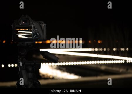 Fotografieren mit der auf dem Stativ montierten Kamera. Verschwommener Blick auf die Lichter der Stadt bei Nacht, Bokeh-Effekt Stockfoto