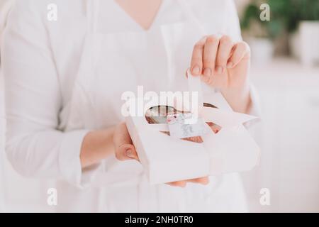 Ein Mädchen in einer weißen Uniform mit schokoladenüberzogenen Erdbeeren in einer Geschenkbox Stockfoto