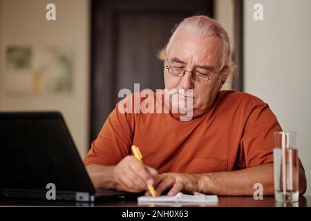 Porträt eines Seniorenmannes, der seine Pläne für den Tag schreibt Stockfoto