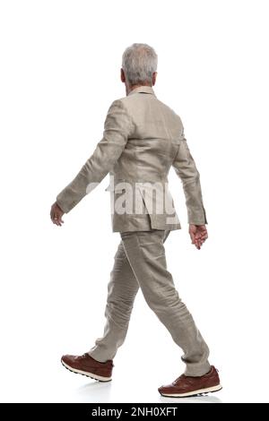 Rückansicht eines alten Mannes mit grauen Haaren, der wegblickt und vor weißem Hintergrund läuft Stockfoto