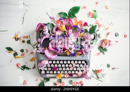Schreibmaschine mit Blumensortiment oben. Stockfoto