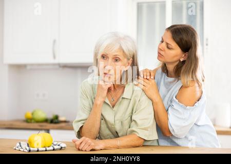Eine Frau tröstet ihre depressive ältere Mutter Stockfoto