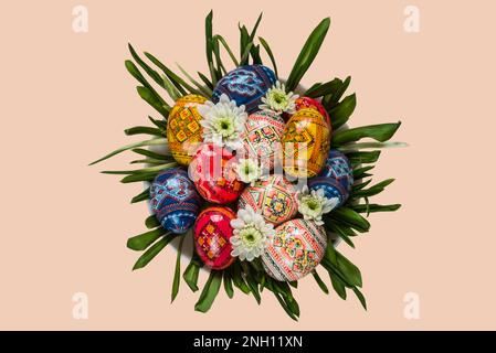 Ostereier und Frühlingsblumen auf grünem Gras auf dem Teller mit isolierter Hintergrundansicht von oben Stockfoto