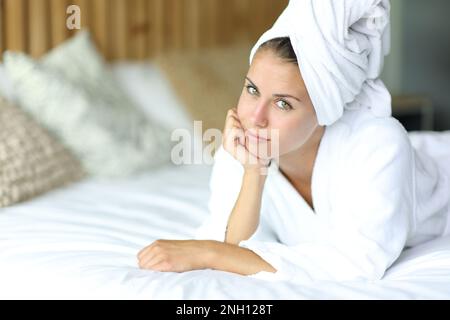 Wunderschöne Frau nach dem Duschen, die auf einem Bett in die Kamera schaut Stockfoto