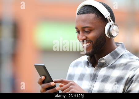 Schwarzer Mann, der draußen auf der Straße Musik hört und telefoniert Stockfoto