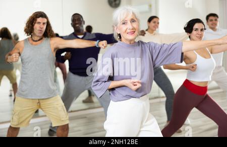 Fröhliche alte Dame, die in der Tanzstunde neue Tänze lernt Stockfoto