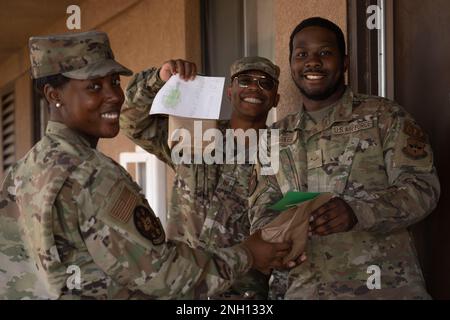 USA Air Force Master Sgt. Alesha Sullivan, 29. Angriffsgeschwader erster Sergeant, links und USA Air Force Master Sgt. Michael Simmons, 49. Logistics Readiness Squadron First Sergeant, Middle, bringen Sie eine Tüte Kekse an Airman 1. Class Jordan Parker, 54. Operations Support Squadron Flugausrüstung Auszubildende, bei der Holloman Air Force, New Mexico, 6. Dezember 2022. Die ersten Sergeants lieferten die Kekstüten persönlich an Airmen, um ihnen von Hollomans Führungsteam frohe Feiertage zu wünschen. Stockfoto