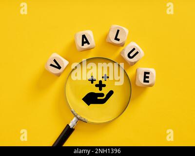 Mehrwert. Wert von Unternehmenswerten oder Servicequalität. Der Wortwert auf Holzwürfeln mit einer Lupe. Stockfoto