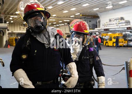 221206-N-CM110-1071 PAZIFIK (6. Dez. 2022) – Seeleute reagieren auf ein simuliertes Opfer von Giftgasen in der Hangarbucht an Bord des Amphibienflugzeugträgers USS Tripoli (LHA 7) 6. Dez. 2022. Tripoli führt gerade Routineeinsätze in der US-3.-Flotte durch. Stockfoto