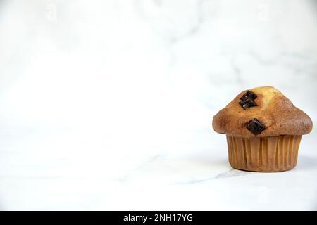 Ein Stapel köstlicher Chocolatechip Banana Muffins und Blaubeeren auf weißem Hintergrund, leckere gesunde Snack Müsli Frühstück Muffin Stockfoto