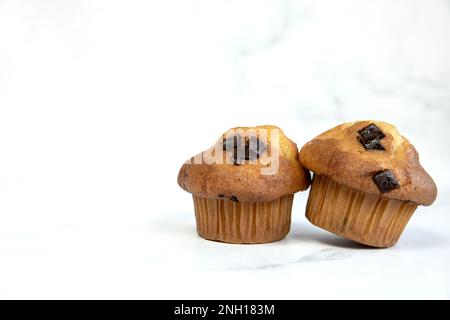 Ein Stapel köstlicher Chocolatechip Banana Muffins und Blaubeeren auf weißem Hintergrund, leckere gesunde Snack Müsli Frühstück Muffin Stockfoto